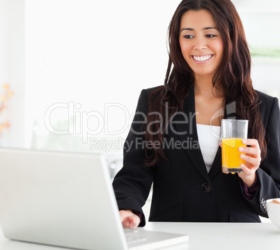 Pretty woman in suit relaxing with her laptop while holding a gl