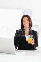 Good looking woman in suit relaxing with her laptop while holdin