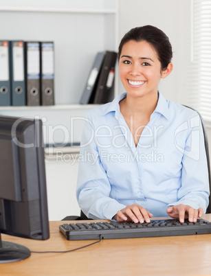 Good looking woman typing on a keyboard while sitting