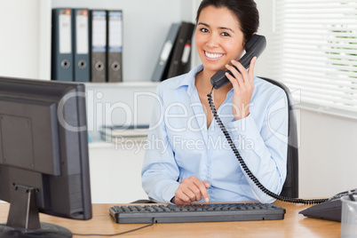 Gorgeous woman on the phone while typing on a keyboard