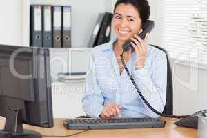 Gorgeous woman on the phone while typing on a keyboard