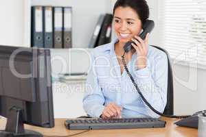 Attractive woman on the phone while typing on a keyboard
