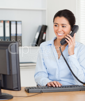 Beautiful woman on the phone while typing on a keyboard