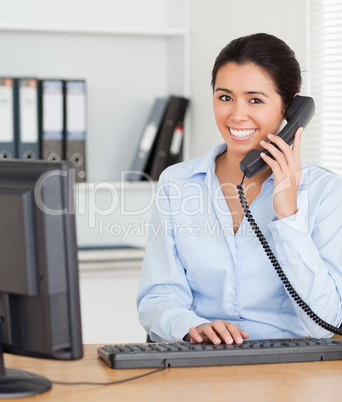 Good looking woman on the phone while typing on a keyboard