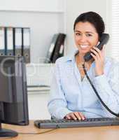 Good looking woman on the phone while typing on a keyboard