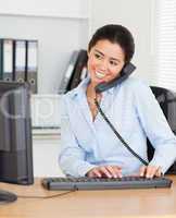 Charming woman on the phone while typing on a keyboard