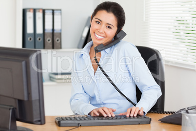 Lovely woman on the phone while typing on a keyboard