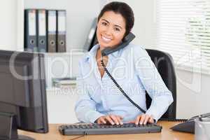 Lovely woman on the phone while typing on a keyboard