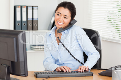 Cute woman on the phone while typing on a keyboard