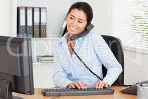 Cute woman on the phone while typing on a keyboard