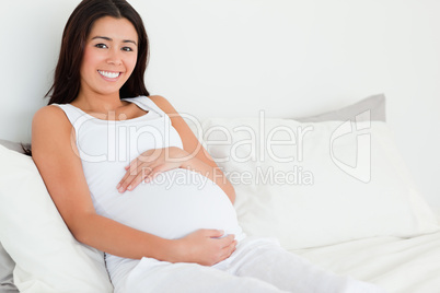 Frontal view of a beautiful pregnant woman touching her belly wh