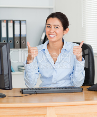 Proud beautiful woman with thumbs up posing while sitting