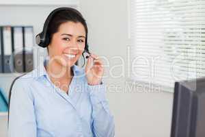 Charming woman with a headset helping customers while sitting