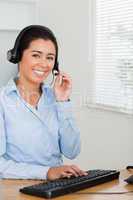 Attractive woman with a headset helping customers while sitting