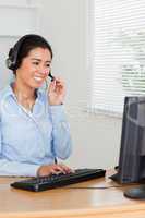 Beautiful woman with a headset helping customers while sitting