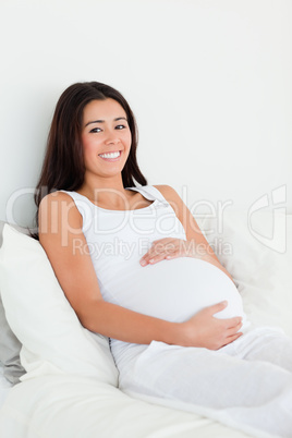 Frontal view of a pretty pregnant woman touching her belly while