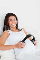 Frontal view of a pretty pregnant woman putting headphones on he