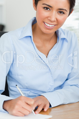 Frontal view of a beautiful woman writing on a sheet of paper wh
