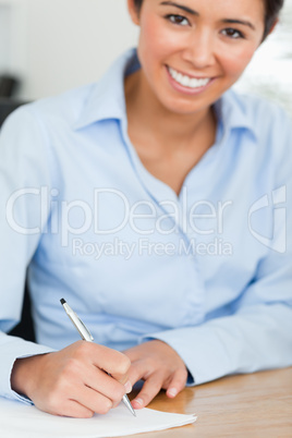 Frontal view of a charming woman writing on a sheet of paper whi
