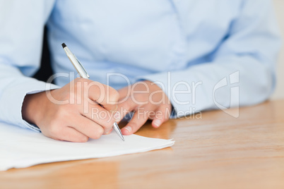 Frontal view of a young woman writing on a sheet of paper while
