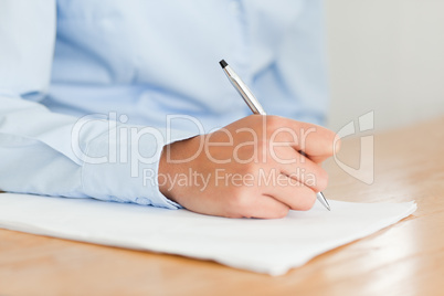 Woman writing on a sheet of paper while sitting