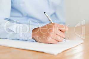 Woman writing on a sheet of paper while sitting