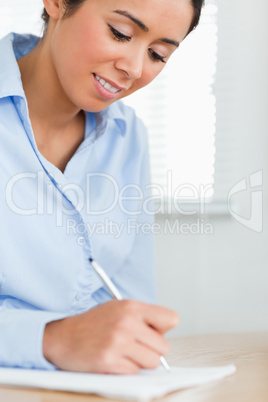 Beautiful woman writing on a sheet of paper while sitting