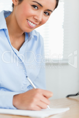Attractive woman writing on a sheet of paper while sitting