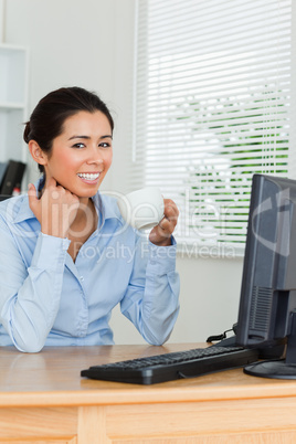 Beautiful woman enjoying a cup of coffee while looking at a comp