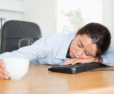 Frontal view of a beautiful woman sleeping on a keyboard while h