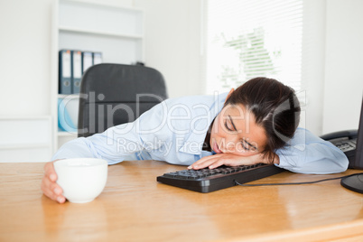 Frontal view of a pretty woman sleeping on a keyboard while hold