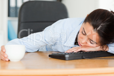 Frontal view of a good looking woman sleeping on a keyboard whil