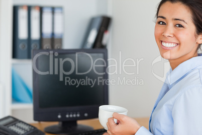Good looking woman holding a cup of coffee while sitting