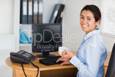 Attractive woman holding a cup of coffee while sitting