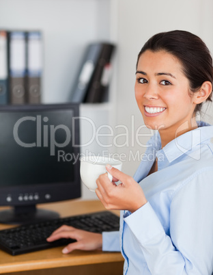 Pretty woman holding a cup of coffee while sitting