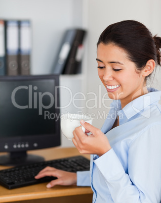 Charming woman holding a cup of coffee while sitting