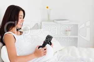 Good looking pregnant woman putting headphones on her belly whil