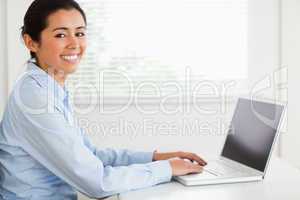 Good looking woman working with her laptop and posing while sitt