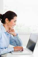 Charming woman working with her laptop and typing while sitting