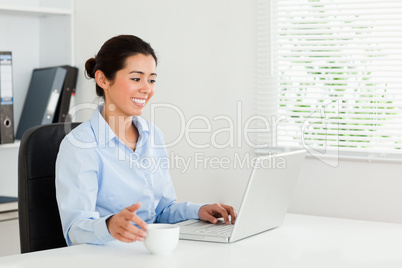 Attractive woman relaxing with her laptop while enjoying a cup o