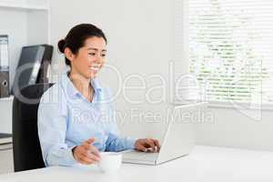Attractive woman relaxing with her laptop while enjoying a cup o
