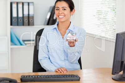 Beautiful woman holding a miniature house while looking at the c