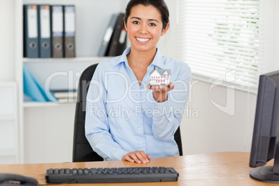 Good looking woman holding a miniature house while looking at th