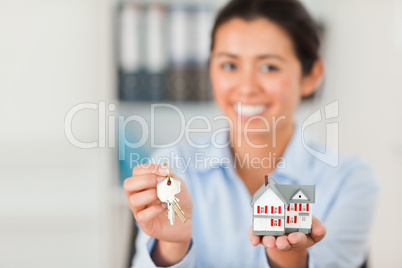 Good looking woman holding keys and a miniature house while look