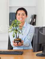 Beautiful woman holding a plant while looking at the camera