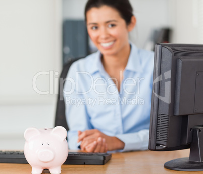 Beautiful woman posing with a piggy bank in front of her