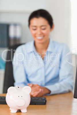 Good looking woman posing with a piggy bank in front of her