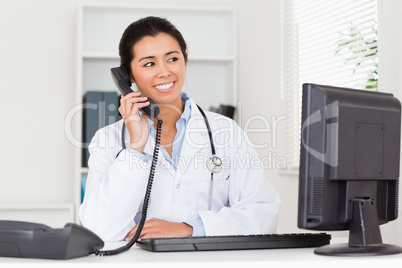 Attractive woman doctor on the phone while sitting