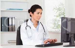Georgeous female doctor typing on a keyboard while sitting