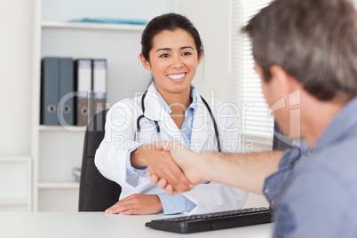 Pretty female doctor shaking a patient's hands
